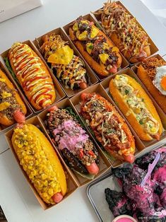 a table topped with lots of different types of hotdogs and corn on the cob