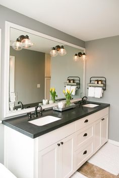 the bathroom has two sinks and black granite countertops with lights on them, along with a large mirror