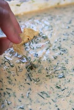 a person dipping something into a bowl of food