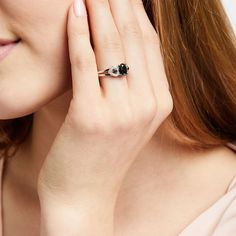 a woman holding her hand up to her face while wearing a black and white ring