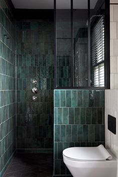 a green tiled bathroom with a white toilet