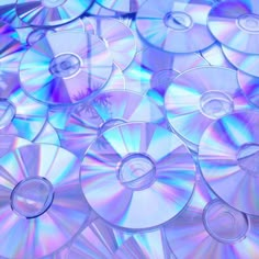 many cd's are stacked on top of each other in blue and purple colors