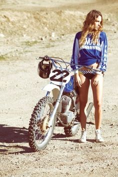 a woman standing next to a dirt bike