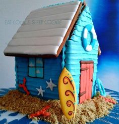 a cake shaped like a house with a surfboard on the beach in front of it