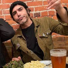 two men sitting at a table with food and drinks