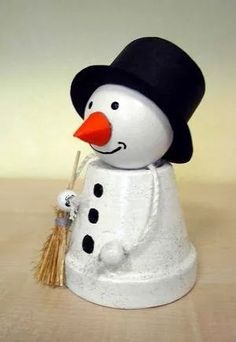 a snowman with a black hat and orange nose is standing on a wooden table