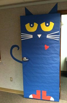 a blue cardboard cat door with yellow eyes