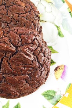 a chocolate cake sitting on top of a white and green plate next to a butterfly