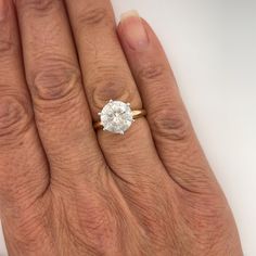 a woman's hand with a diamond ring on top of her left hand, showing the center stone