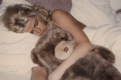 a woman laying in bed with a teddy bear