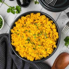 a bowl filled with yellow rice next to other dishes and utensils on a table