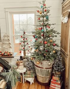 a small christmas tree in a bucket with ornaments on it and other decorations around the base