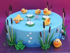 a blue cake decorated with little yellow ducks and water lilies