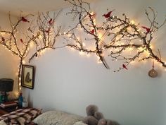 a bedroom decorated for christmas with lights on the wall and branches hanging over the bed