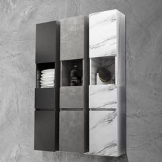 a white and black bathroom with marble wall tiles on the walls, an open cabinet that has towels in it