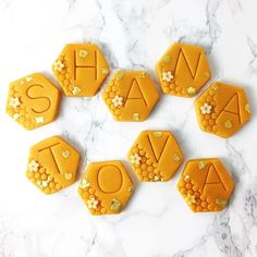 six cookies decorated with the word ava spelled by honeycombs on a marble surface