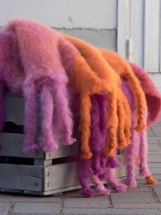 an orange and pink octopus stuffed animal sitting on top of a wooden pallet next to a white door