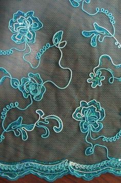 an embroidered table cloth with blue flowers on it