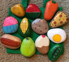 an assortment of painted rocks on a green mat with a bag in the middle,