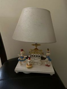 a lamp sitting on top of a table next to a small toy train and figurines