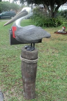 a statue of a pelican on top of a mailbox in the grass