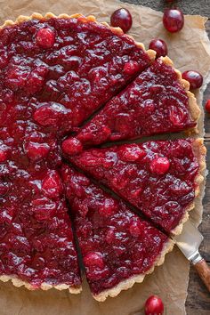 a pie with cranberry sauce on top is cut into slices and sits on a piece of parchment paper