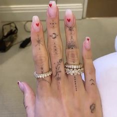 a woman's hand with three different tattoos on her fingers and two rings in the middle