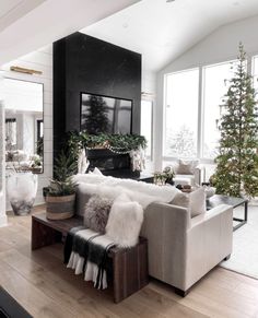 a living room filled with furniture and a fire place next to a christmas tree on top of a hard wood floor