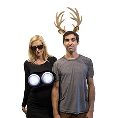 a man and woman standing next to each other in front of a wall with antlers on it