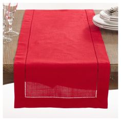 a red table runner on top of a wooden table with place settings and silverware