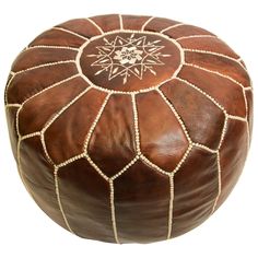 a brown leather ottoman with white stitching on the top and an embroidered design on the bottom