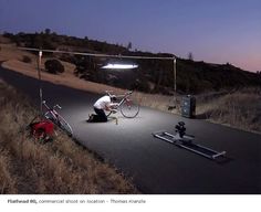 a man is setting up his bike on the road at night with lights and equipment around him