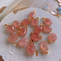 a bunch of pink stones sitting on top of a white plate next to some gold chains