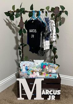 a wooden crate filled with baby items next to a t - shirt and name sign