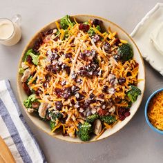 a bowl filled with broccoli, cheese and other foods next to a glass of milk