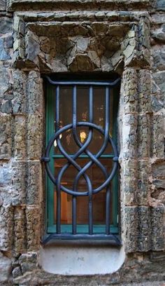 an iron window on the side of a stone building