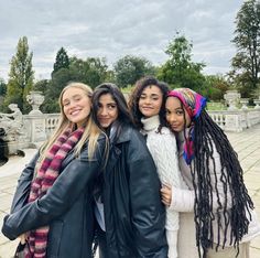 four girls are standing together in front of a fountain