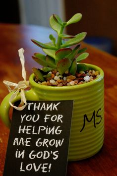 a small potted plant sitting on top of a table next to a sign that says thank you for helping me grow in god's love