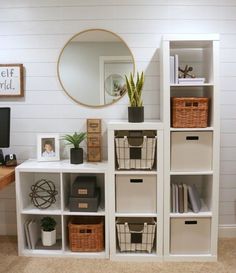 a white shelf filled with lots of boxes and bins next to a wall mounted mirror