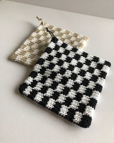 two black and white crocheted pouches sitting on top of a table next to each other