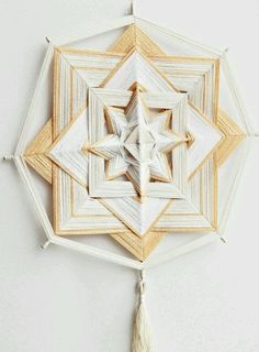 an origami star hanging on the wall with tassels