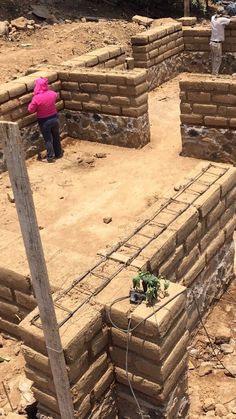 two people are standing in the middle of a construction site with brick walls and fencing around them