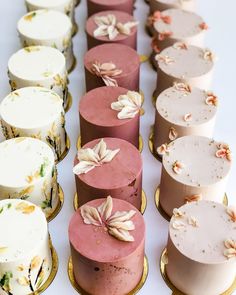 several cakes with flowers on them are lined up in rows and ready to be eaten