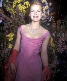 a woman in a purple dress standing next to flowers