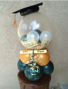 balloons and money are stacked on top of each other in front of a graduation cap