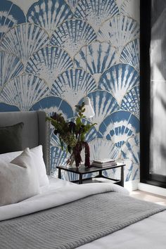 a bedroom with a large bed and wallpaper in shades of blue, white and grey