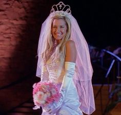 a woman in a wedding dress holding a bouquet and wearing a tiara on her head