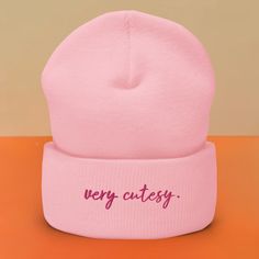 a pink hat with the word very cute written on it's front and side