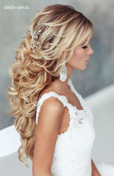 a woman with long blonde hair wearing a white dress and pearls in her hair is looking off to the side