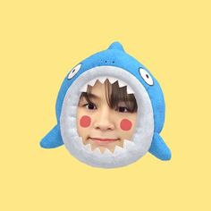 a child's face is shown through a shark - shaped stuffed animal toy head